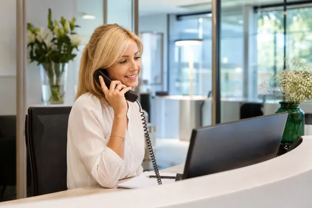 Standardiste répondant au téléphone derrière le comptoir d'accueil d'un bureau