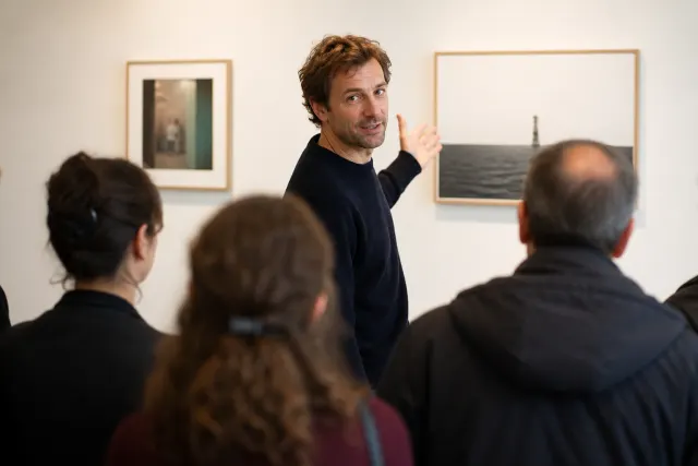 Médiateur culturel commentant une œuvre devant un groupe de visiteurs